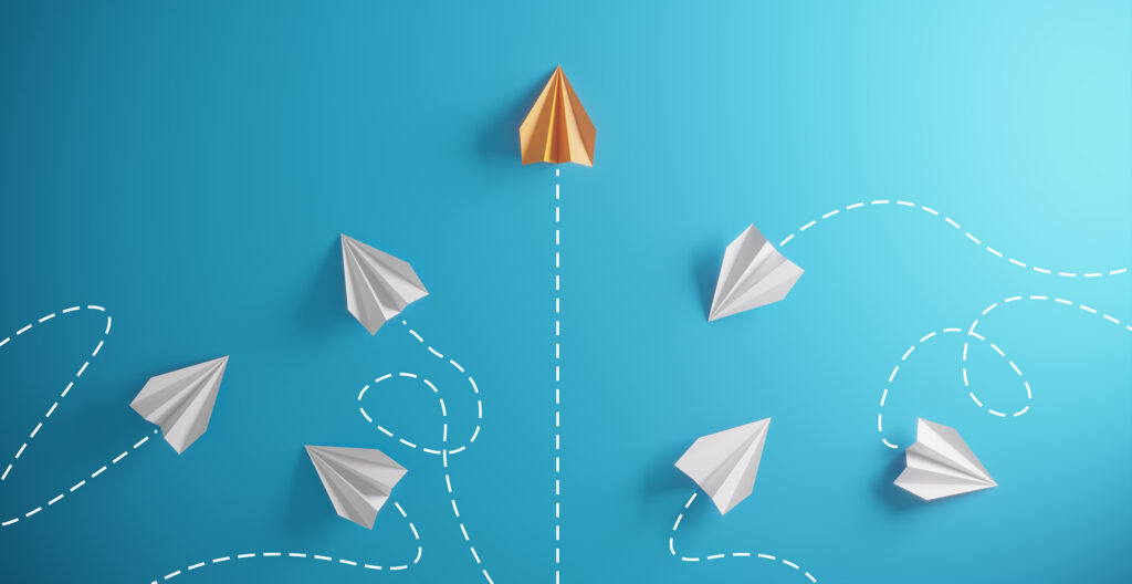 Conceptual graphic of nonprofit change management. Group of paper airplanes flying in different directions with one plane passing through with success.
