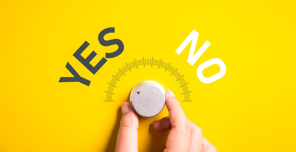 Hand turning a volume selector labeled 'Yes' and 'No,' symbolizing decision-making and flexibility in nonprofit leadership.